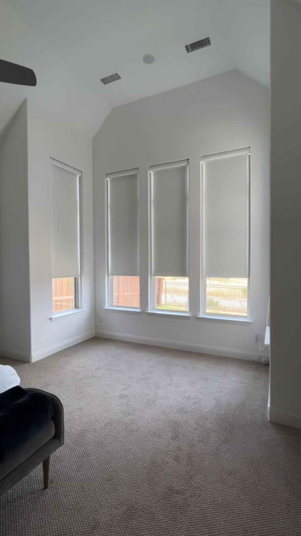 A bedroom with a lot of windows and blinds on them.