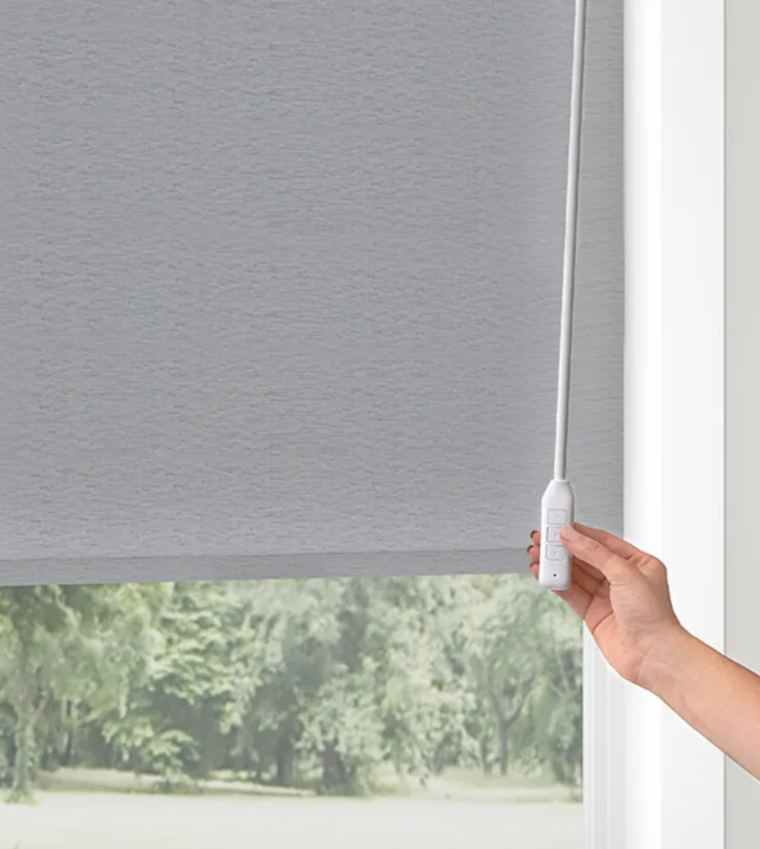 A person is pulling a cord on a roller blind on a window.