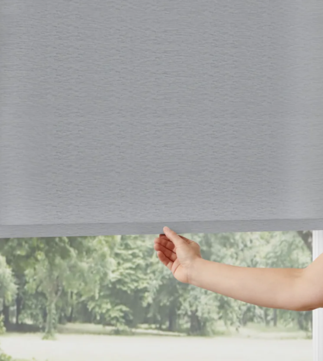 A person is holding a roller blind in front of a window.