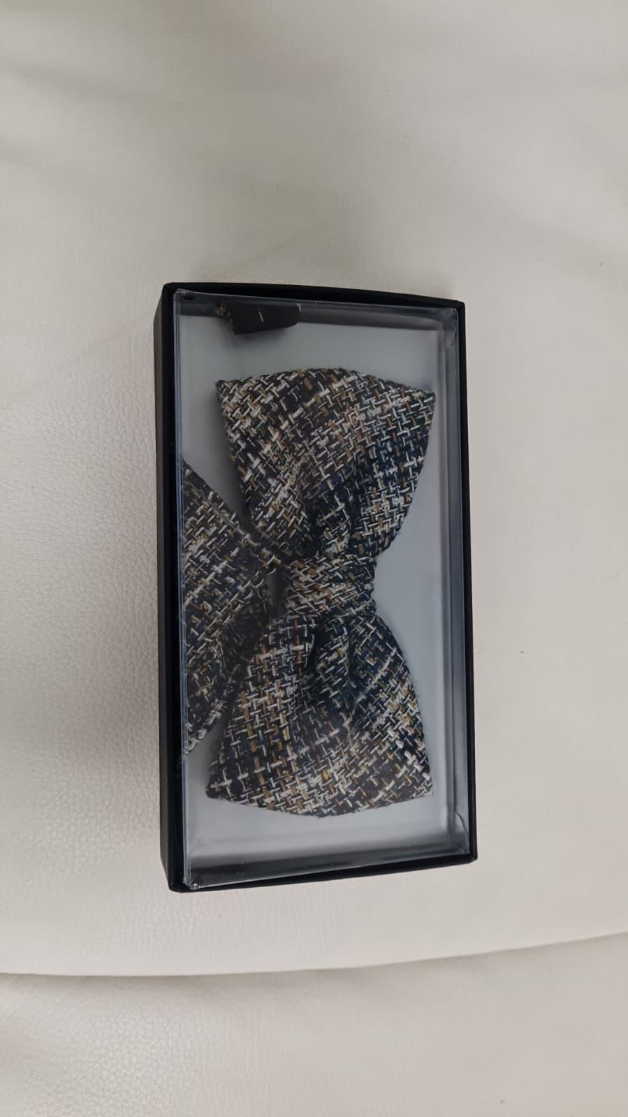 Eine Fliege liegt in einer Schachtel auf einer weißen Fläche.