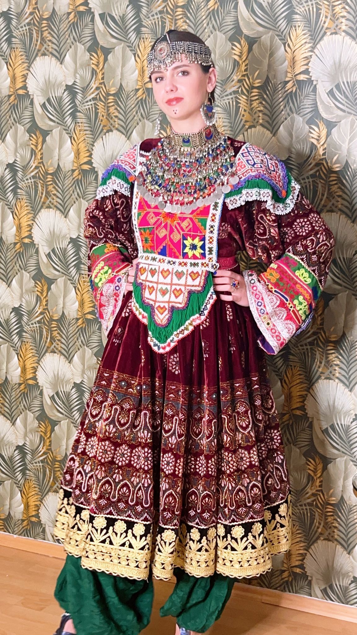 Eine Frau in einem bunten Kleid steht vor einer Wand.