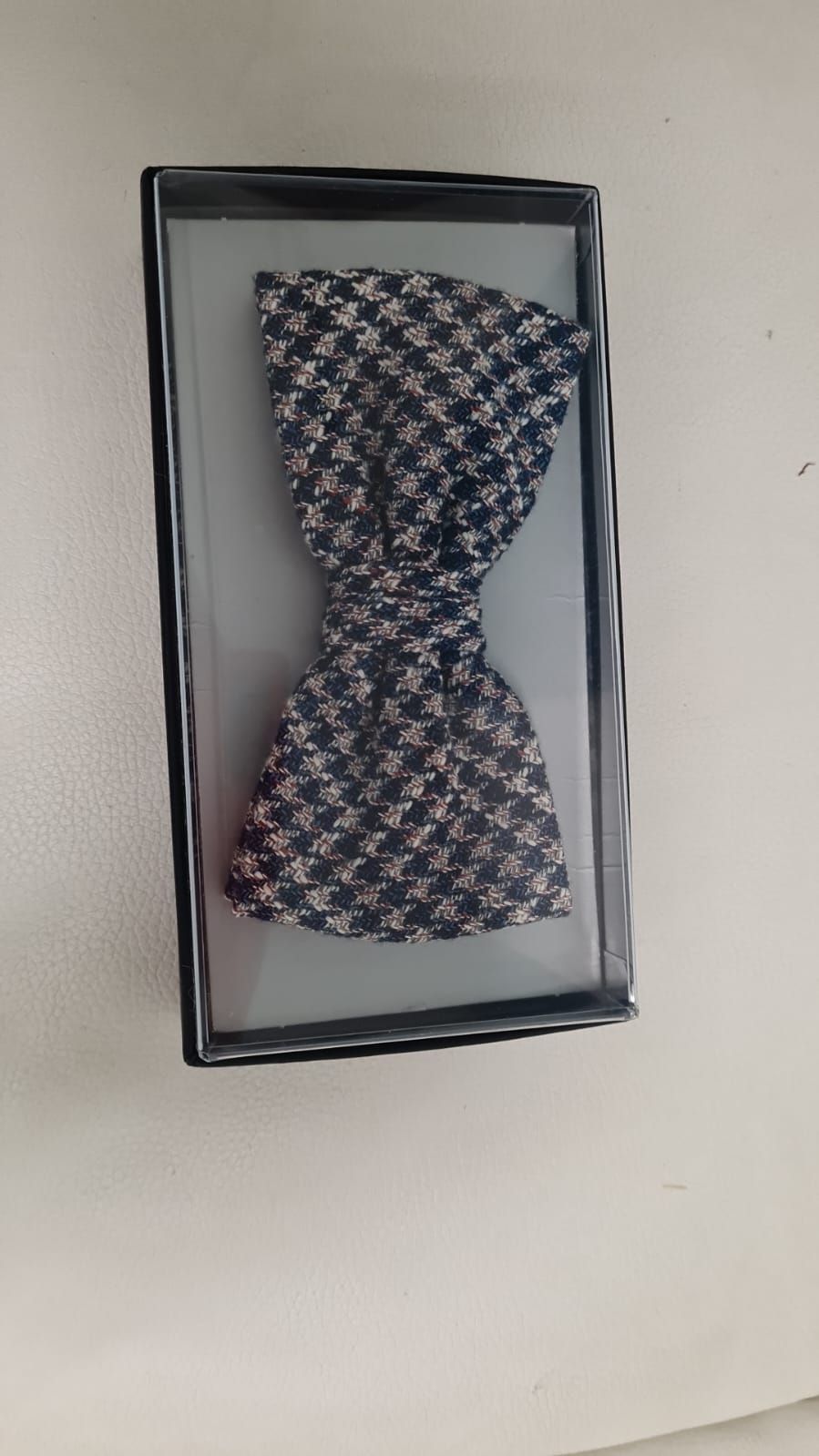 Eine schwarz-weiße Fliege liegt in einer Schachtel auf einem Tisch.