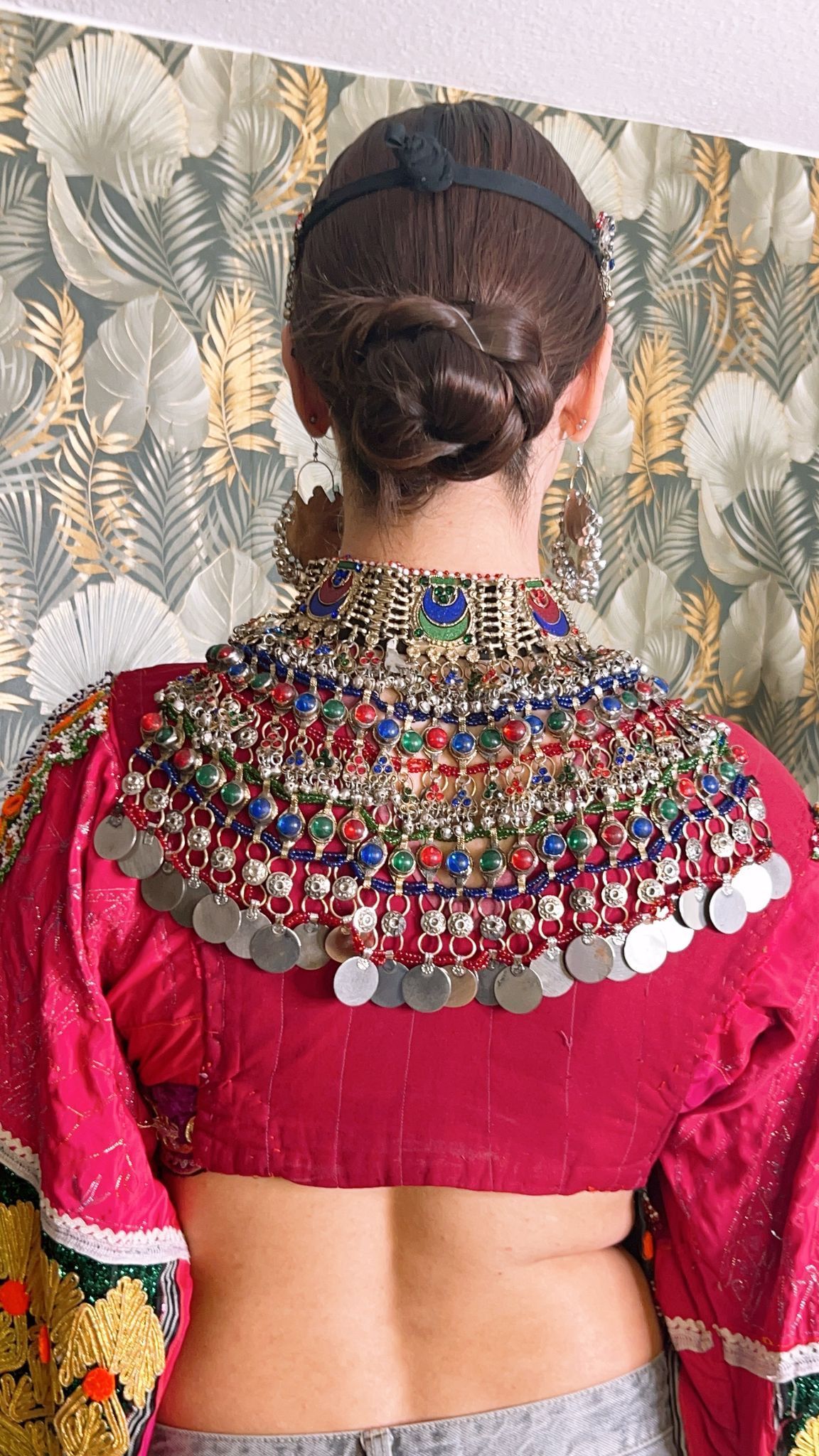 Der Rücken einer Frau, die eine rosa Bluse mit Münzen darauf trägt.