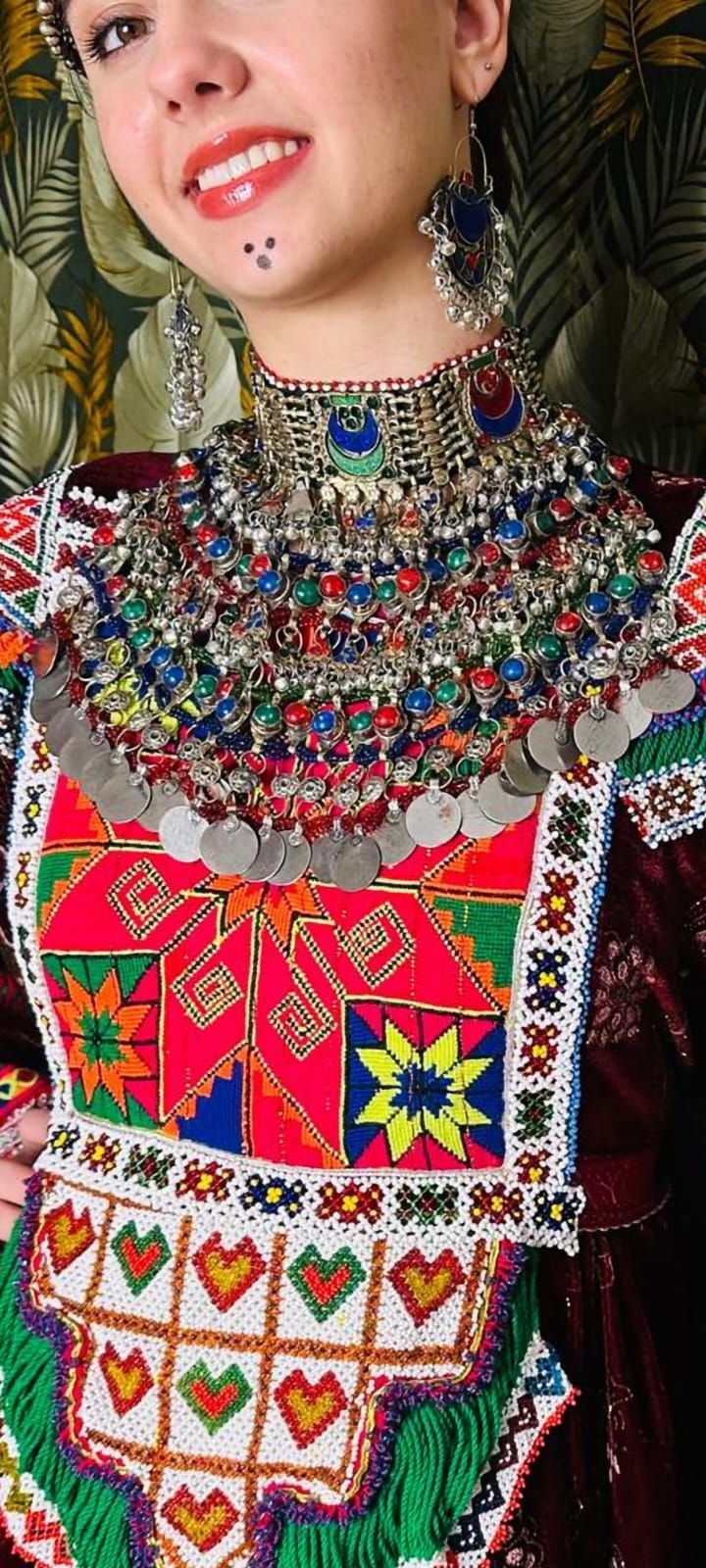 Eine Frau trägt ein buntes Kleid und eine Halskette.