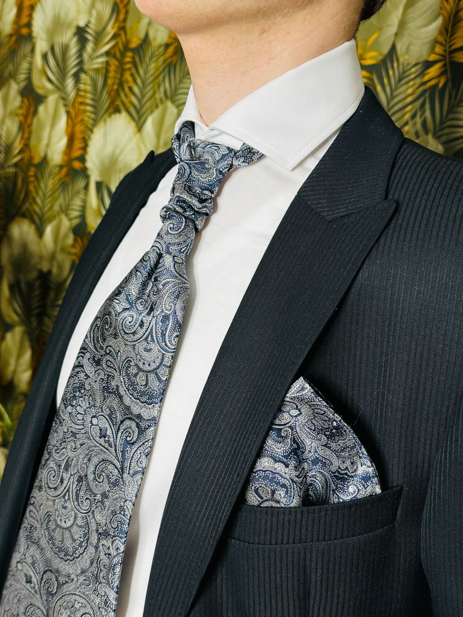 Ein Mann im Anzug und mit Krawatte hat ein Einstecktuch in der Tasche.