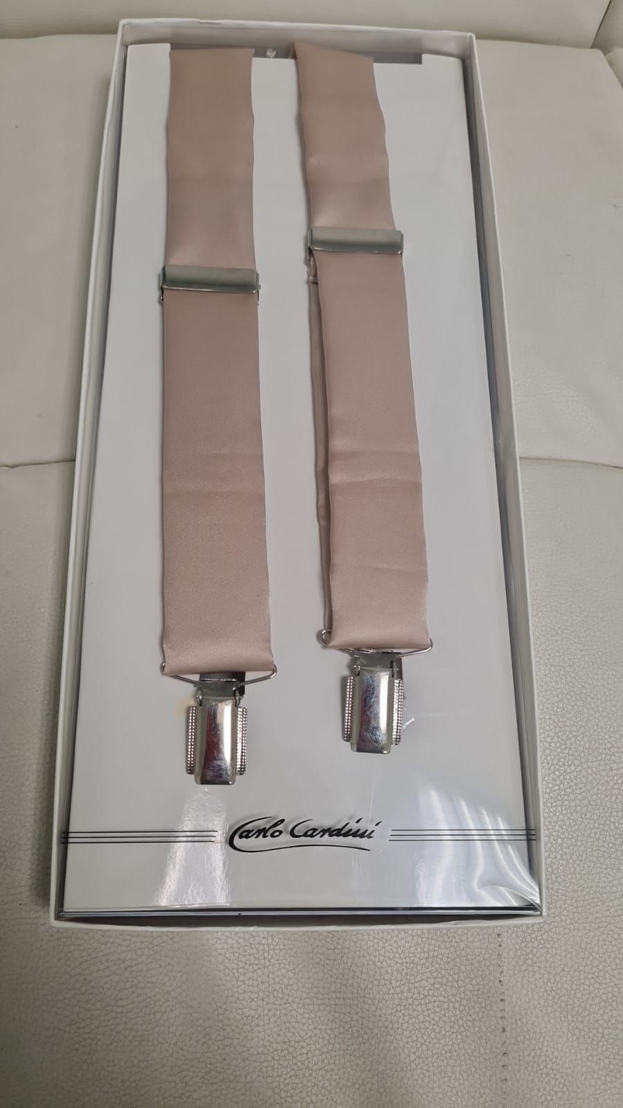 Ein Paar Hosenträger in einer Schachtel auf einem Sofa.