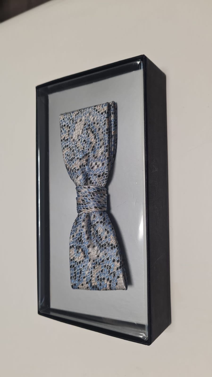 Ein Bild einer Fliege in einer Schachtel an einer Wand.