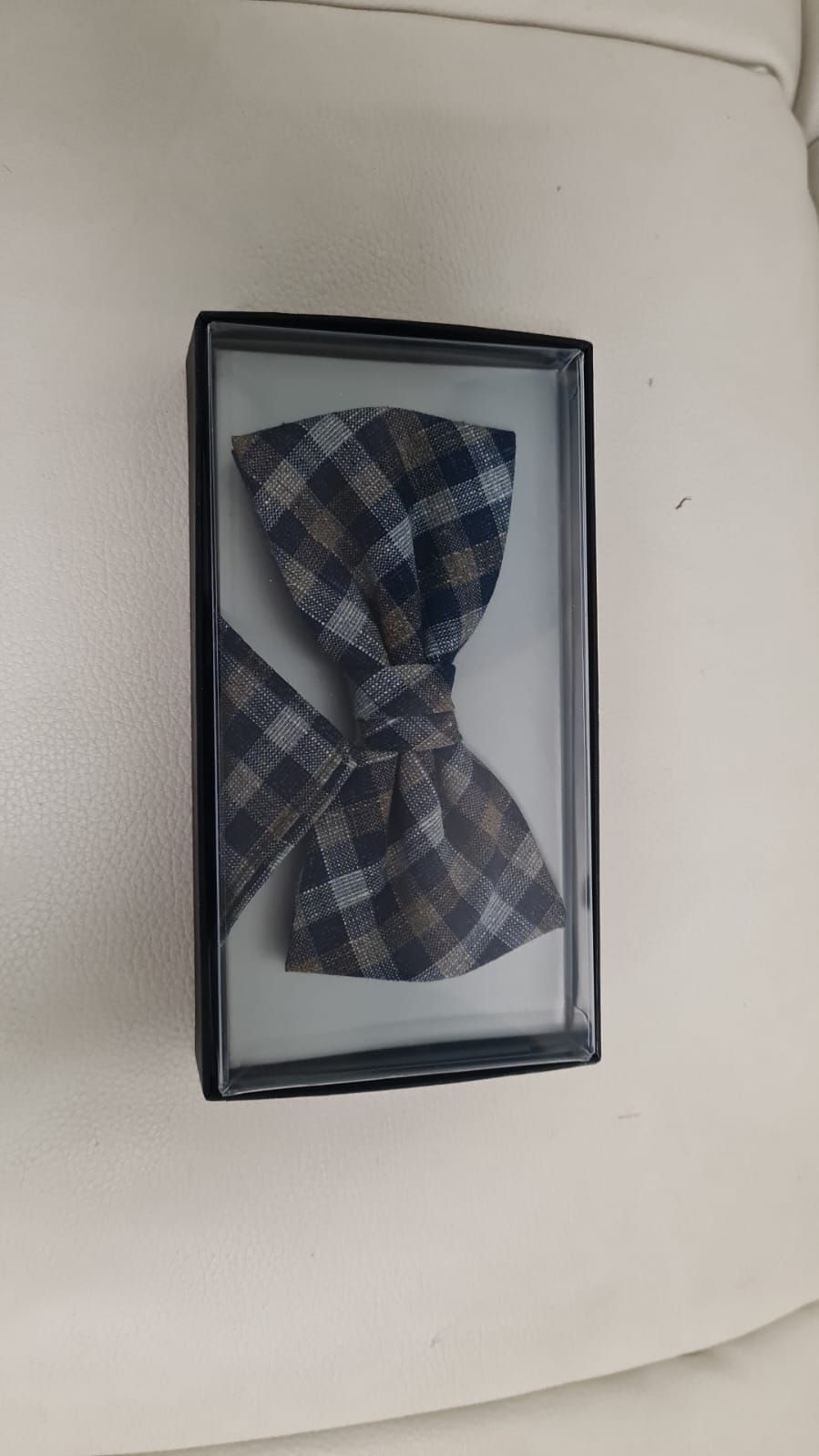 Eine Fliege liegt in einer Schachtel auf einer weißen Fläche.