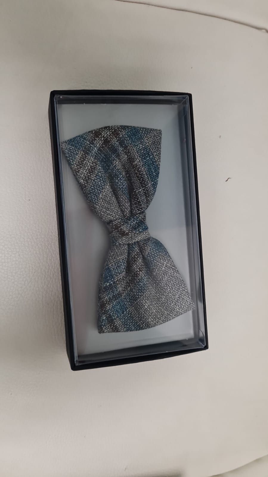 Eine Fliege liegt in einer Schachtel auf einer weißen Fläche.