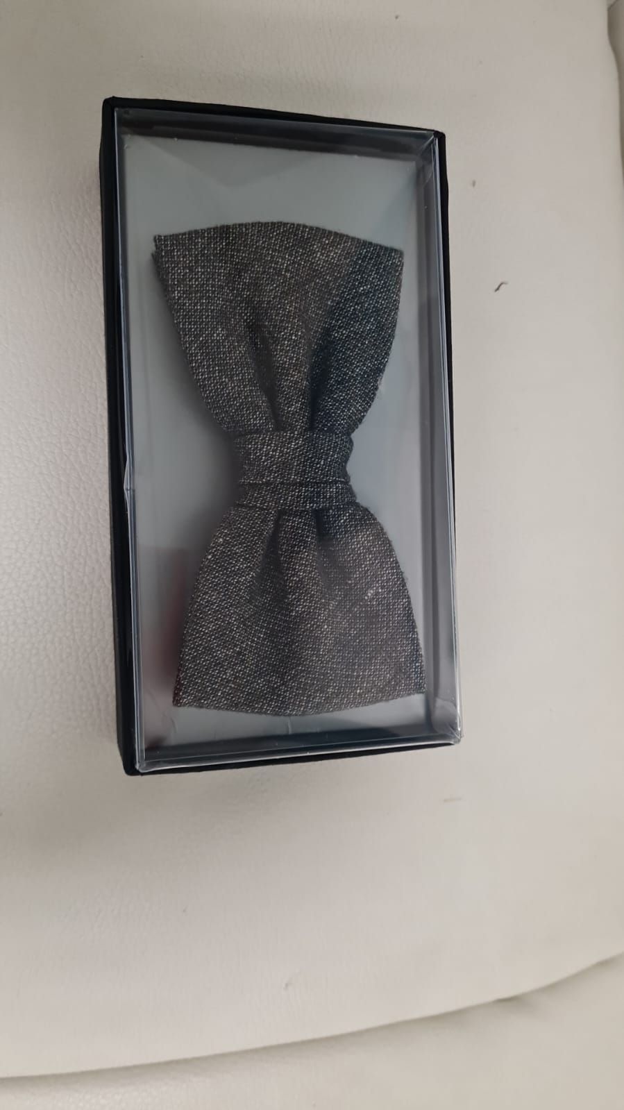 Eine Fliege liegt in einer Schachtel auf einer weißen Fläche.