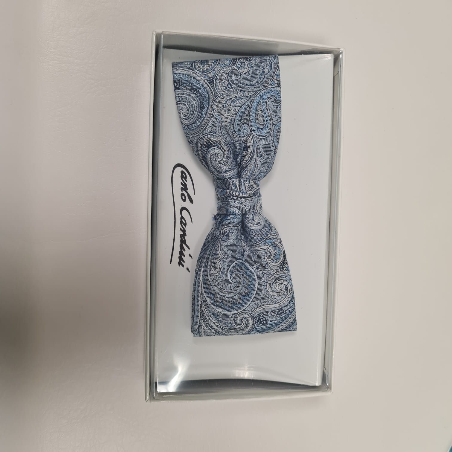 In einer Schachtel befindet sich eine blau-weiße Fliege.