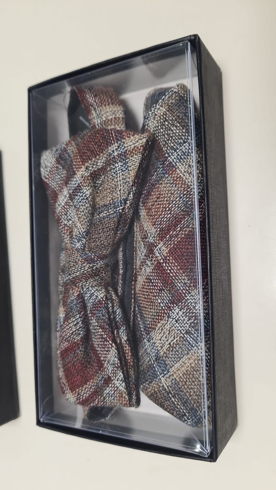 Eine Fliege und ein Einstecktuch befinden sich in einer Schachtel.