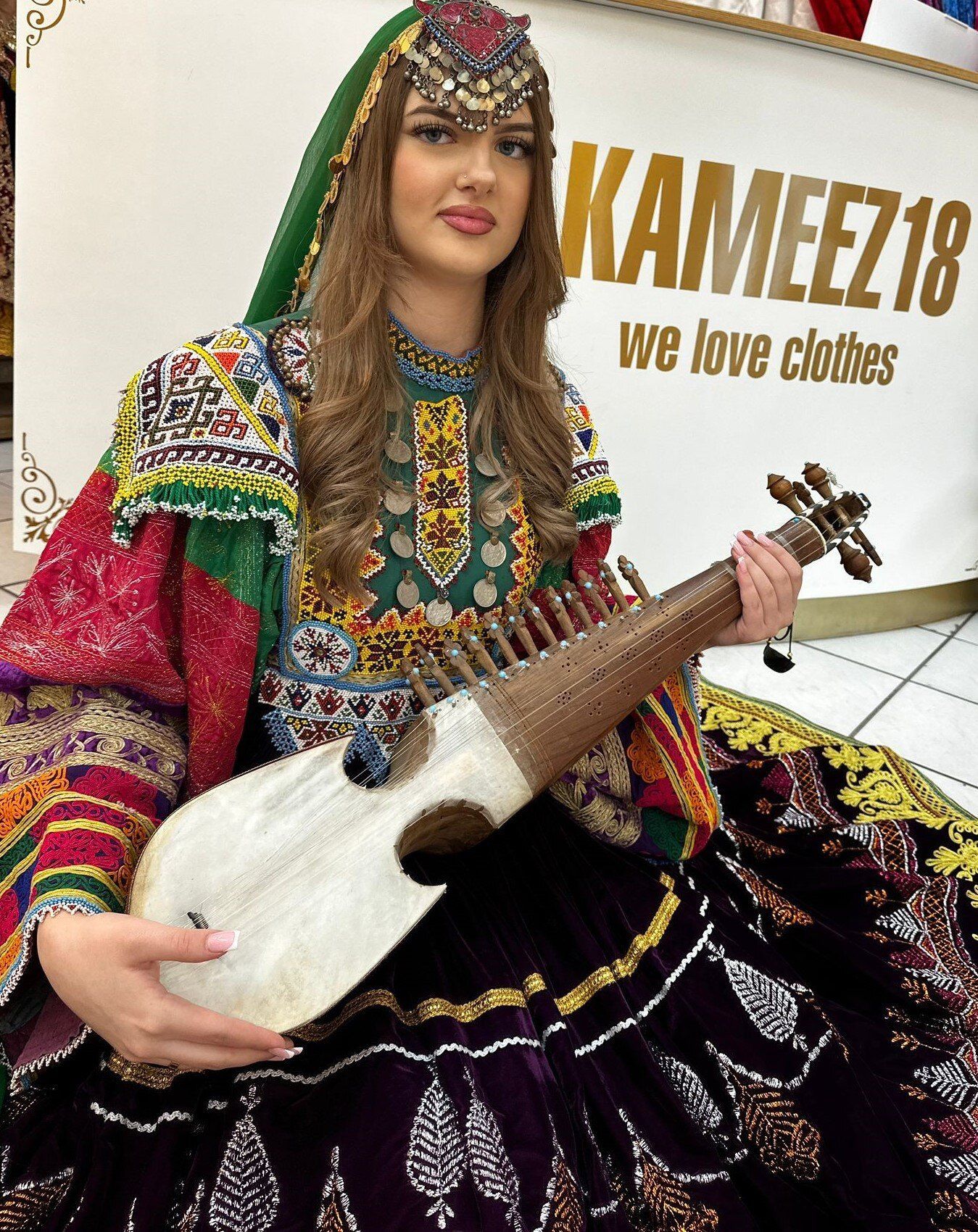 Eine Frau in einem bunten Kleid hält eine Gitarre.