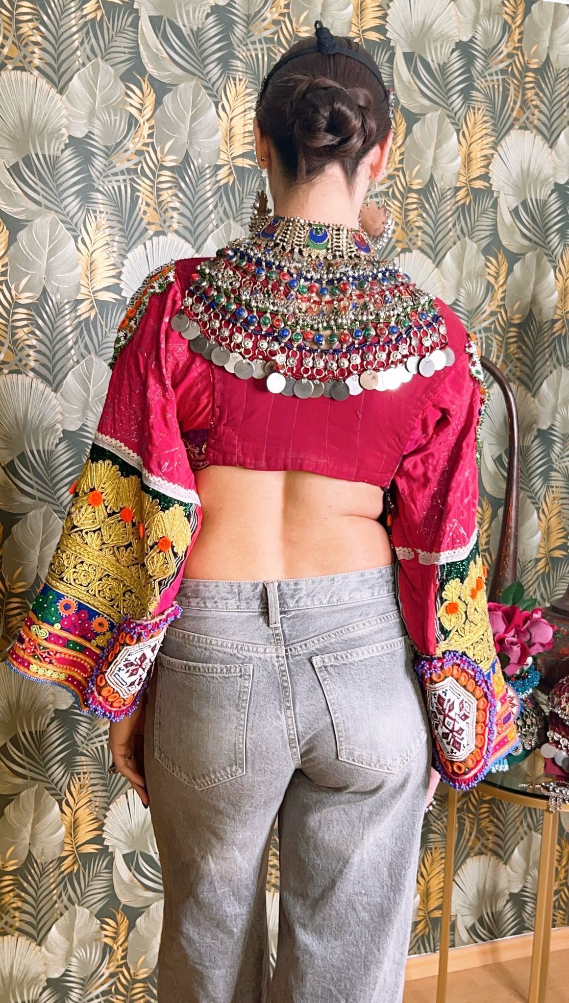 Der Rücken einer Frau, die ein rotes bauchfreies Top und graue Jeans trägt.