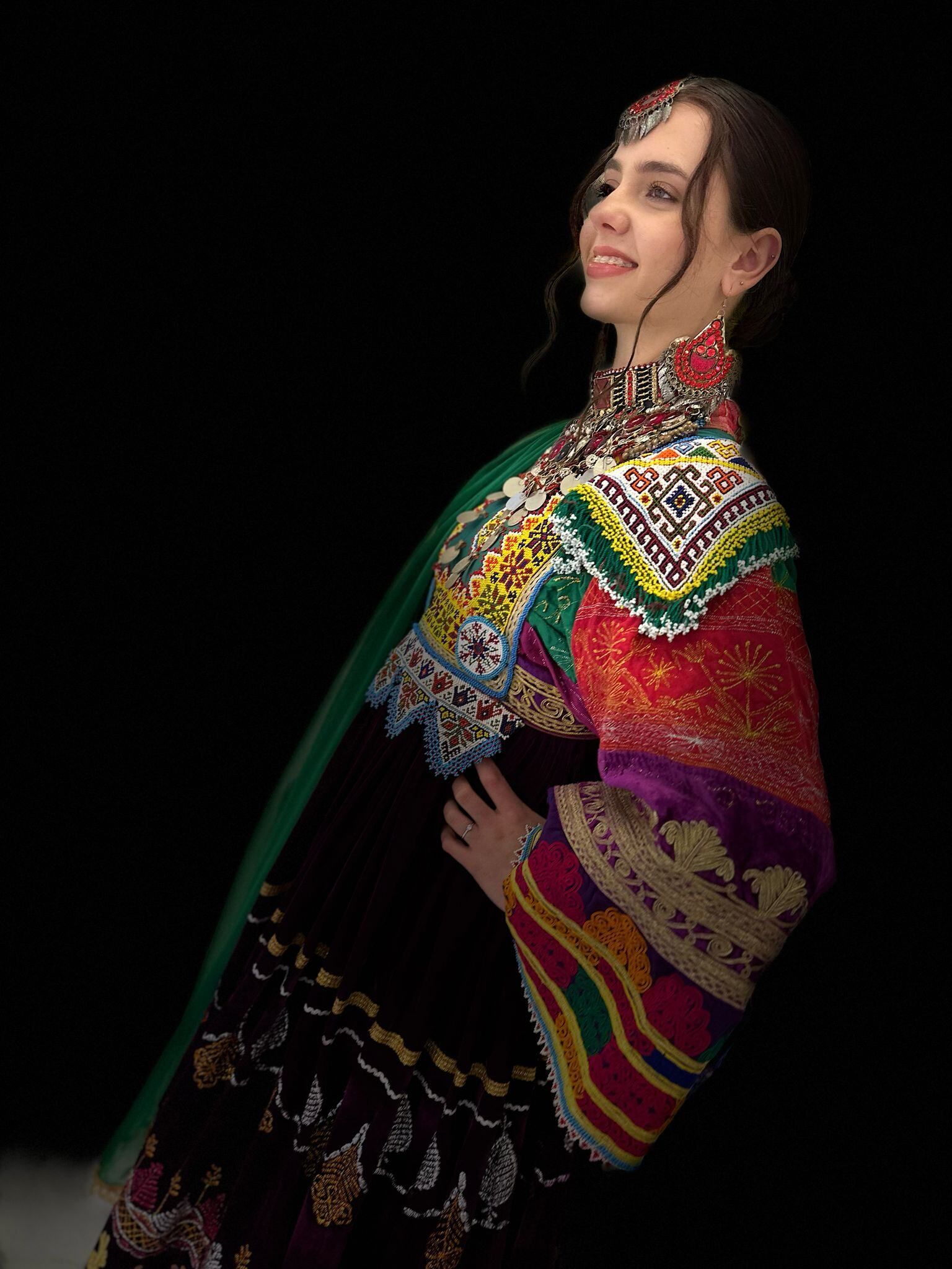 Eine Frau in einem bunten Kleid steht vor einem schwarzen Hintergrund.