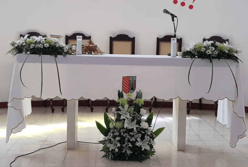Una mesa con flores y un micrófono encima.
