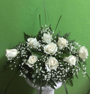 Un jarrón lleno de rosas blancas y flores de bebé.