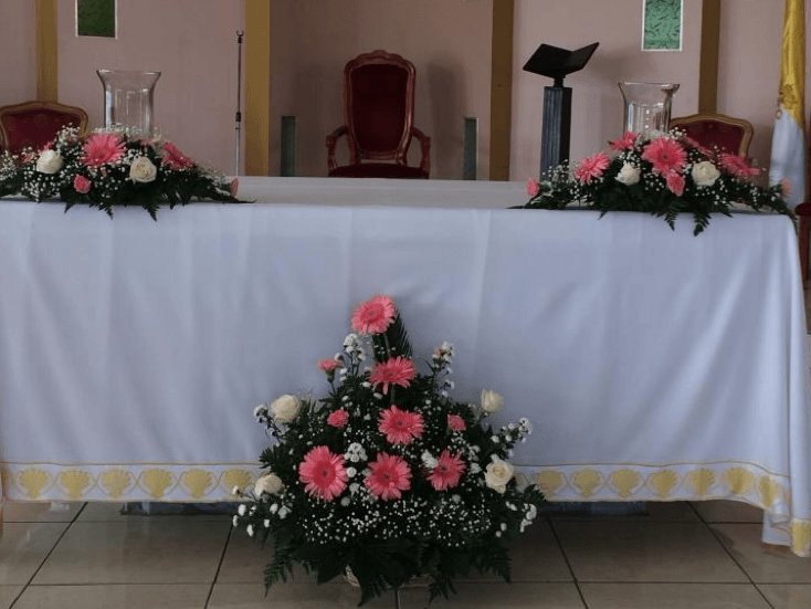 Una mesa blanca con flores rosas y blancas sobre ella.