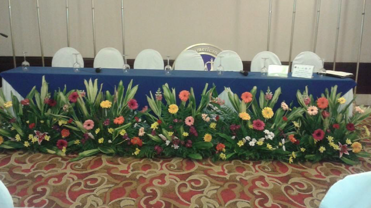 Una mesa larga con flores en una habitación.