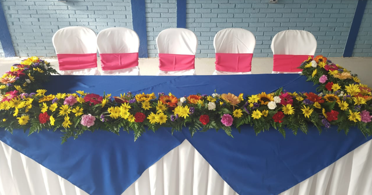 Una mesa con un mantel azul y flores sobre ella.