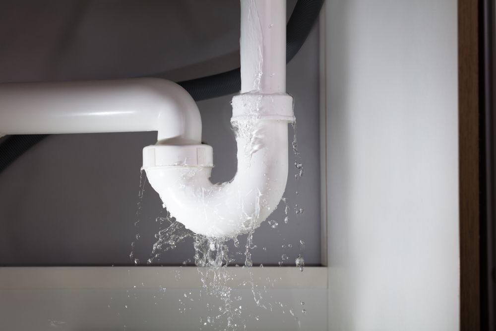 A sink pipe is leaking water under a sink.