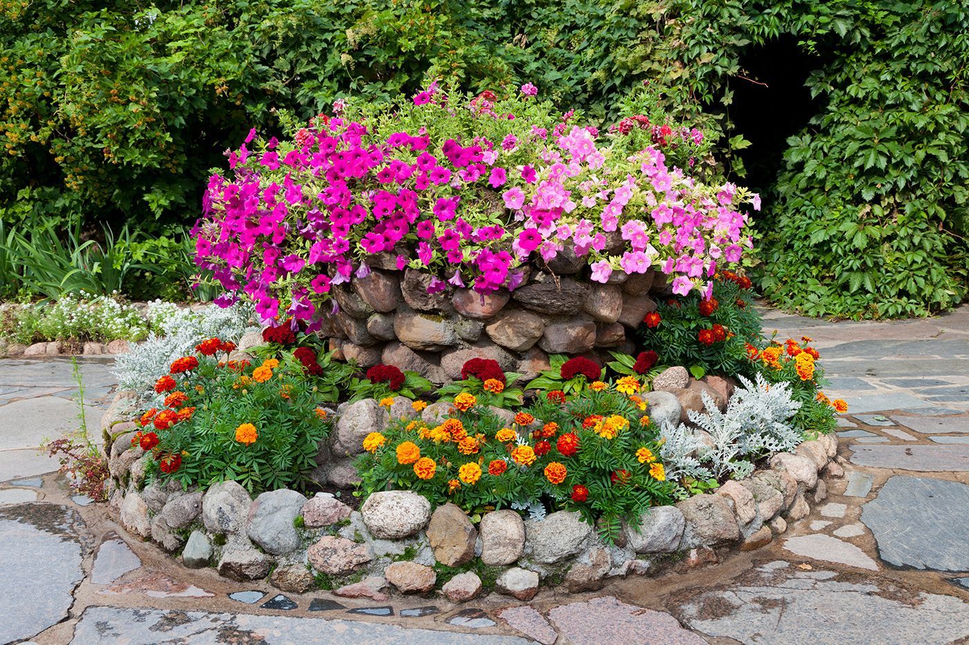 A stone planter filled with pink and orange flowers
