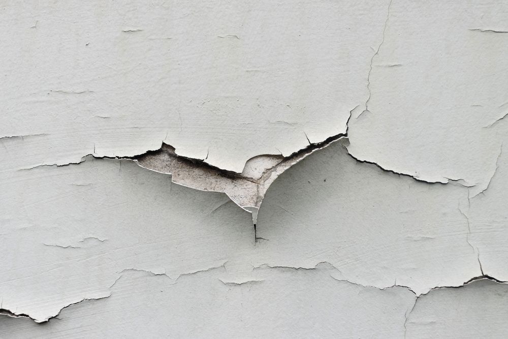 A close up of a white wall with peeling paint