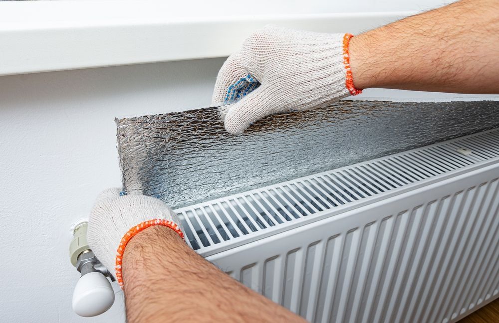 A person is cutting a piece of metal on a radiator.
