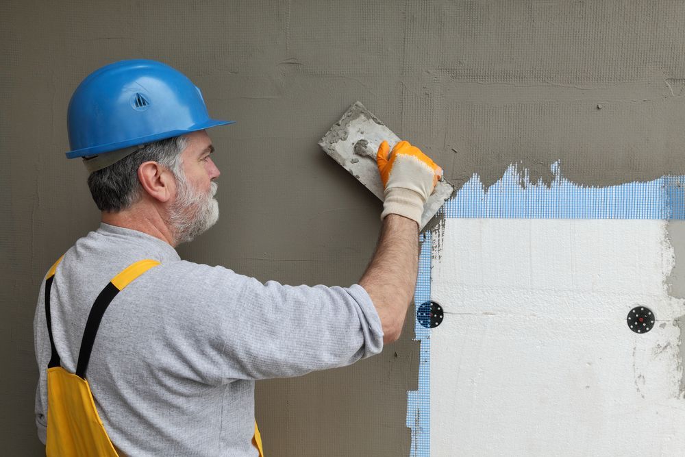 A man is plastering a wall with a spatula.