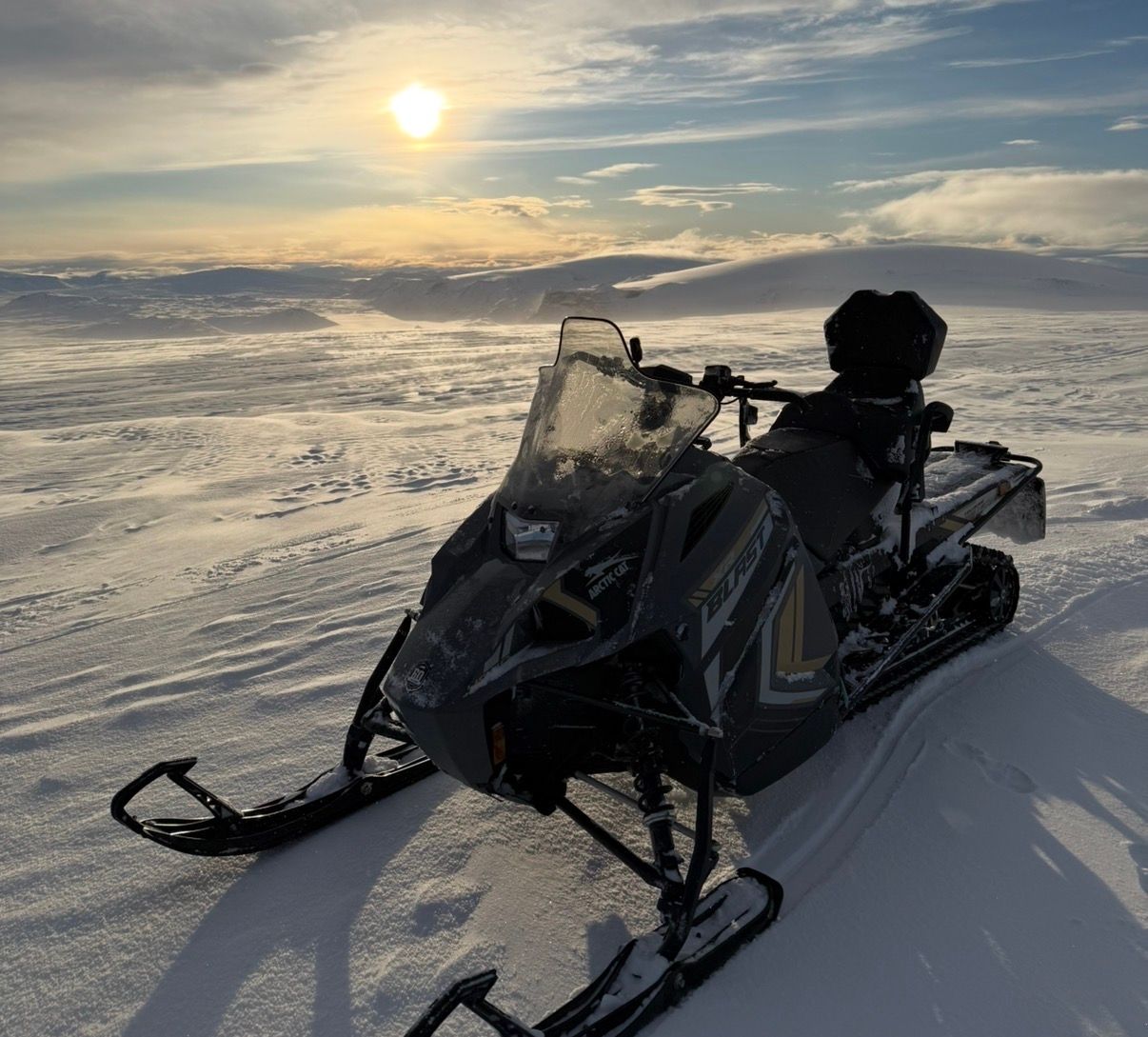 Snowmobile on a snow-covered landscape under a bright sun.