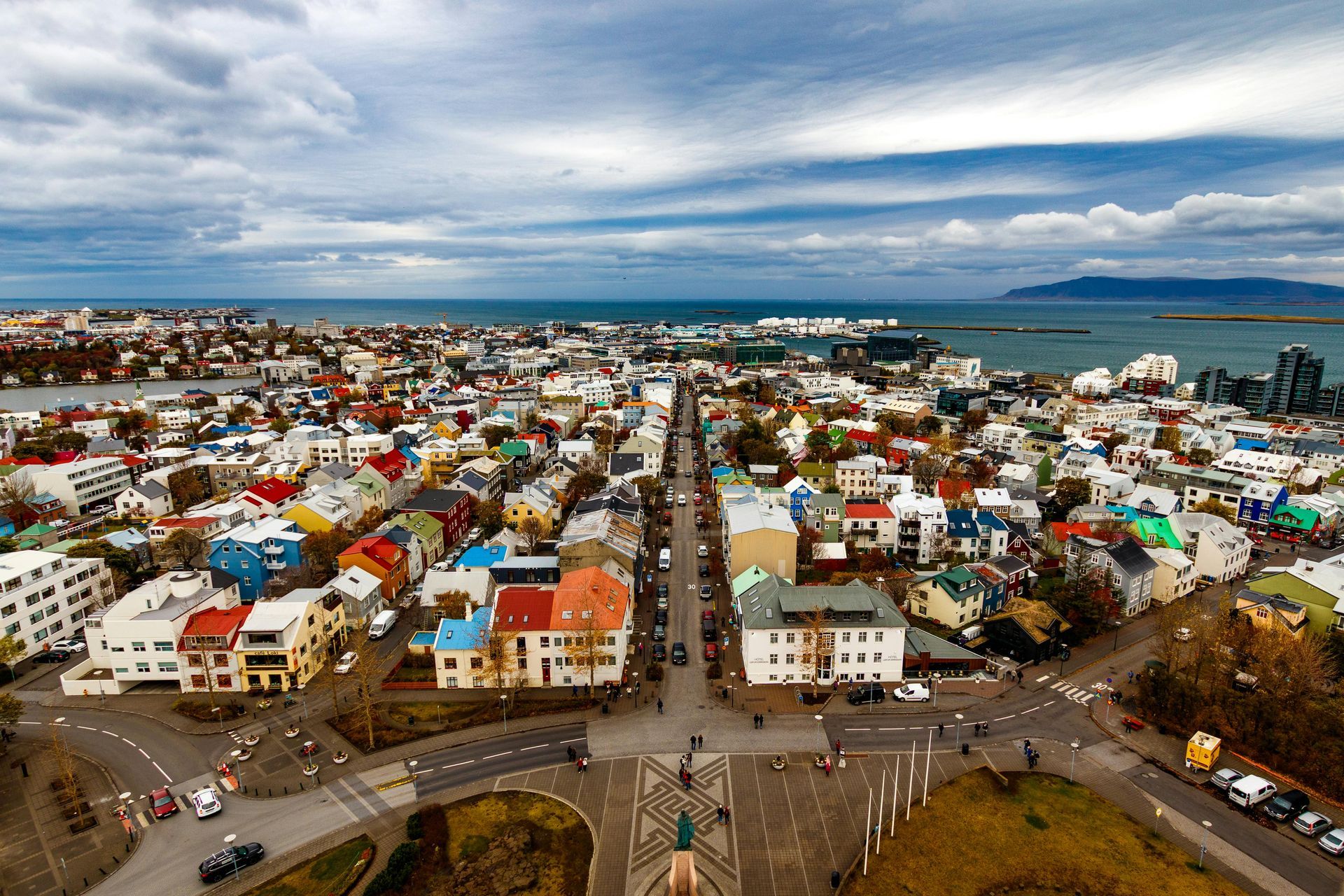 Cityscape of Reykjavik, Iceland, with colorful buildings, ocean backdrop, and cloudy sky.