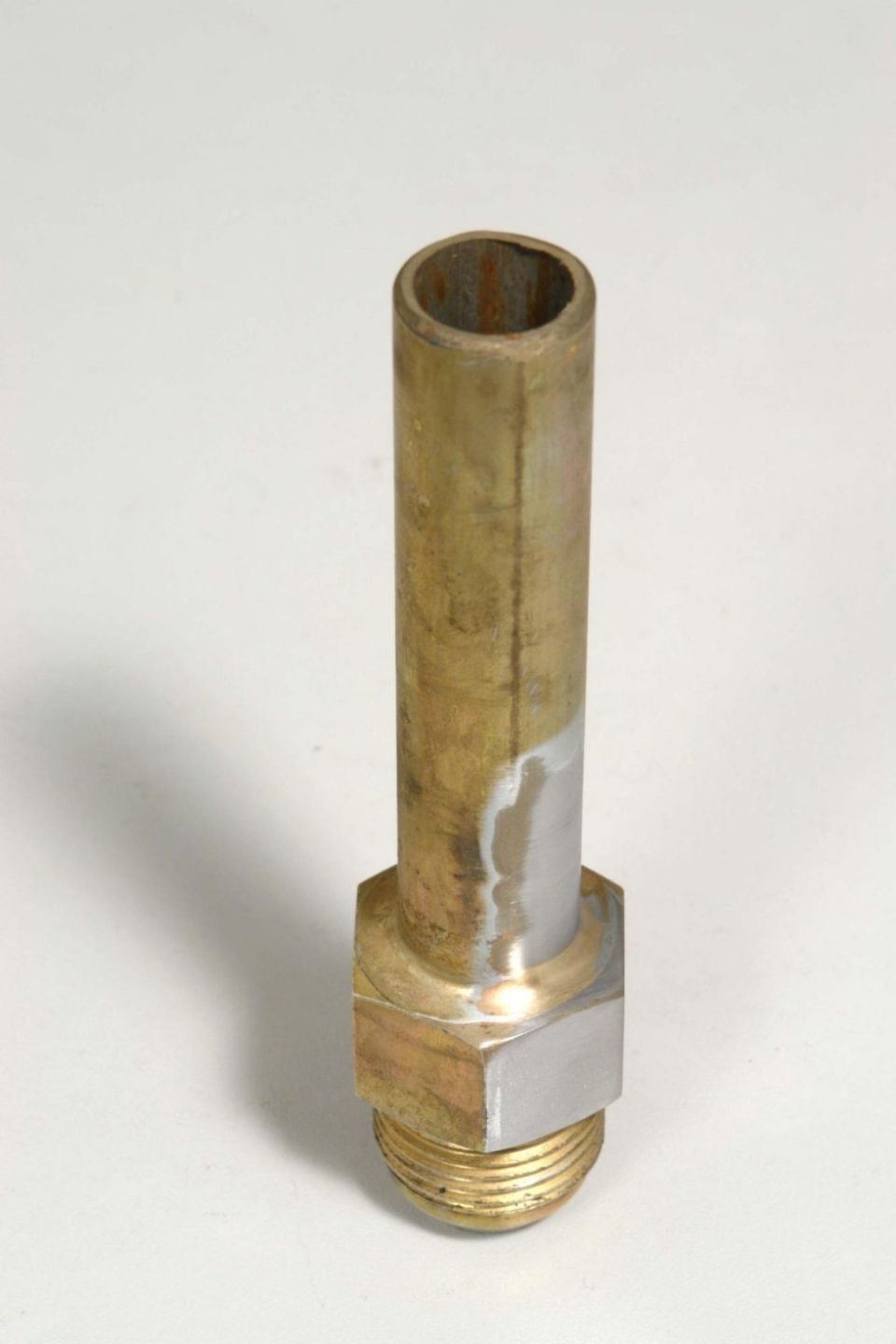 Primo piano di un tubo di ottone su una superficie bianca.