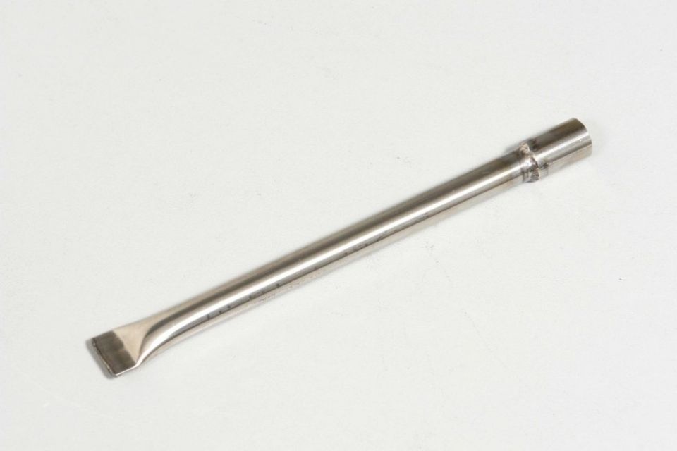 Un cacciavite in acciaio inossidabile è appoggiato su una superficie bianca.