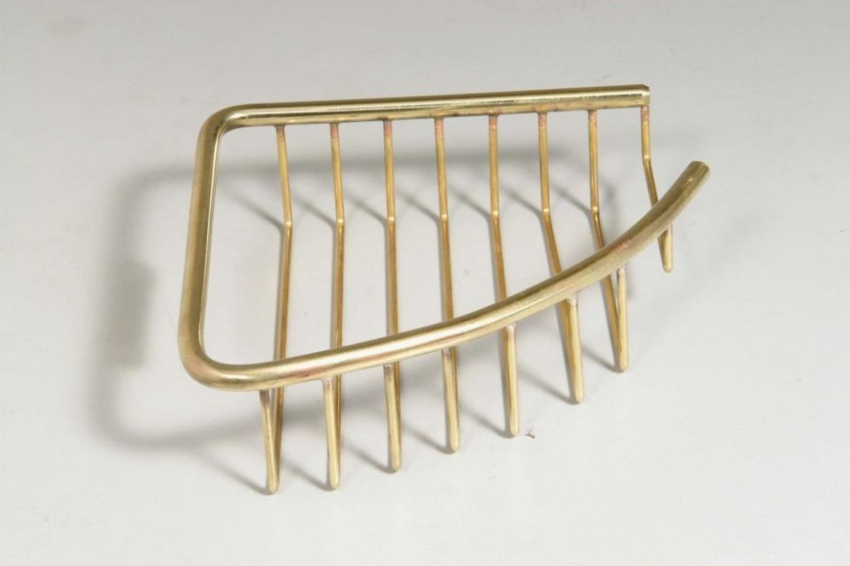 Un pettine per capelli in ottone è appoggiato su una superficie bianca