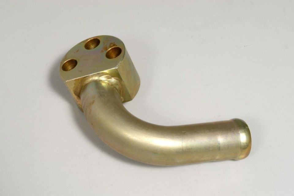 Primo piano di un tubo di ottone su una superficie bianca.