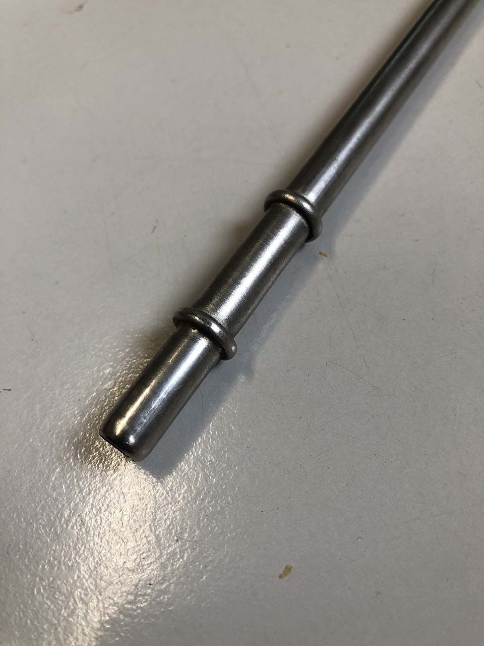 Un primo piano di un tubo metallico su una superficie bianca