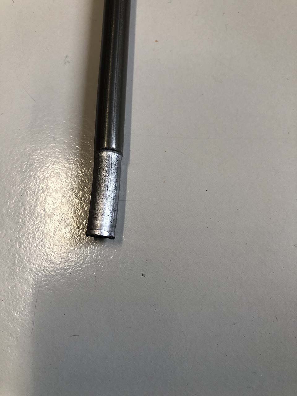 Primo piano di un'asta di metallo su una superficie bianca.