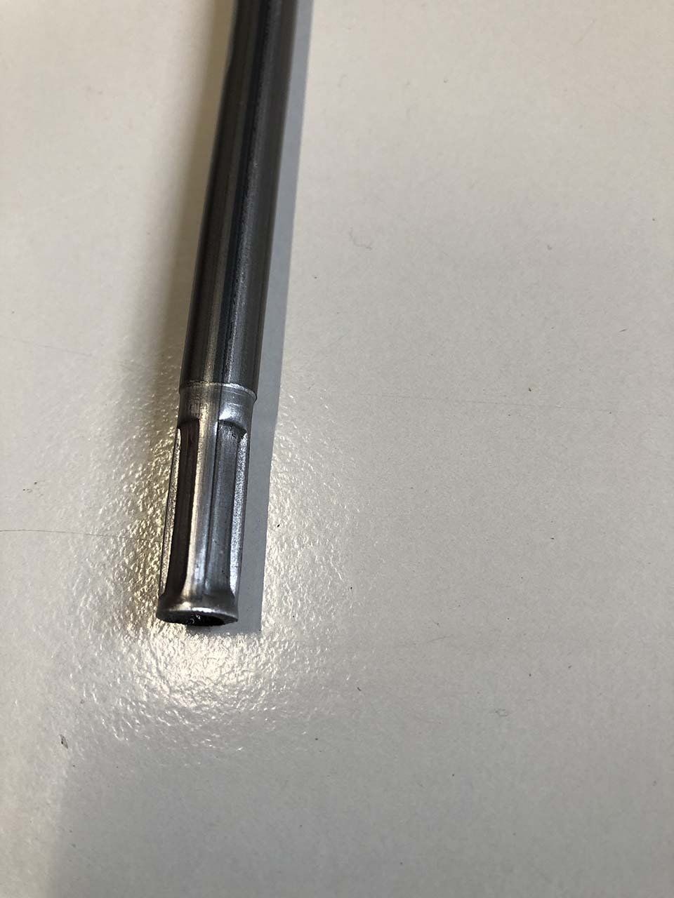 Primo piano di un tubo metallico su una superficie bianca.