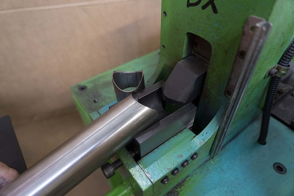 Una persona sta tagliando un tubo di metallo con una macchina.