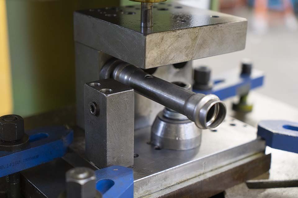 Una macchina sta tagliando un tubo di metallo su un tavolo.