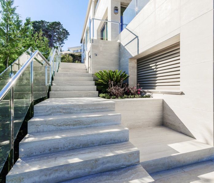 Una rampa di scale che porta a una casa con una ringhiera di vetro.