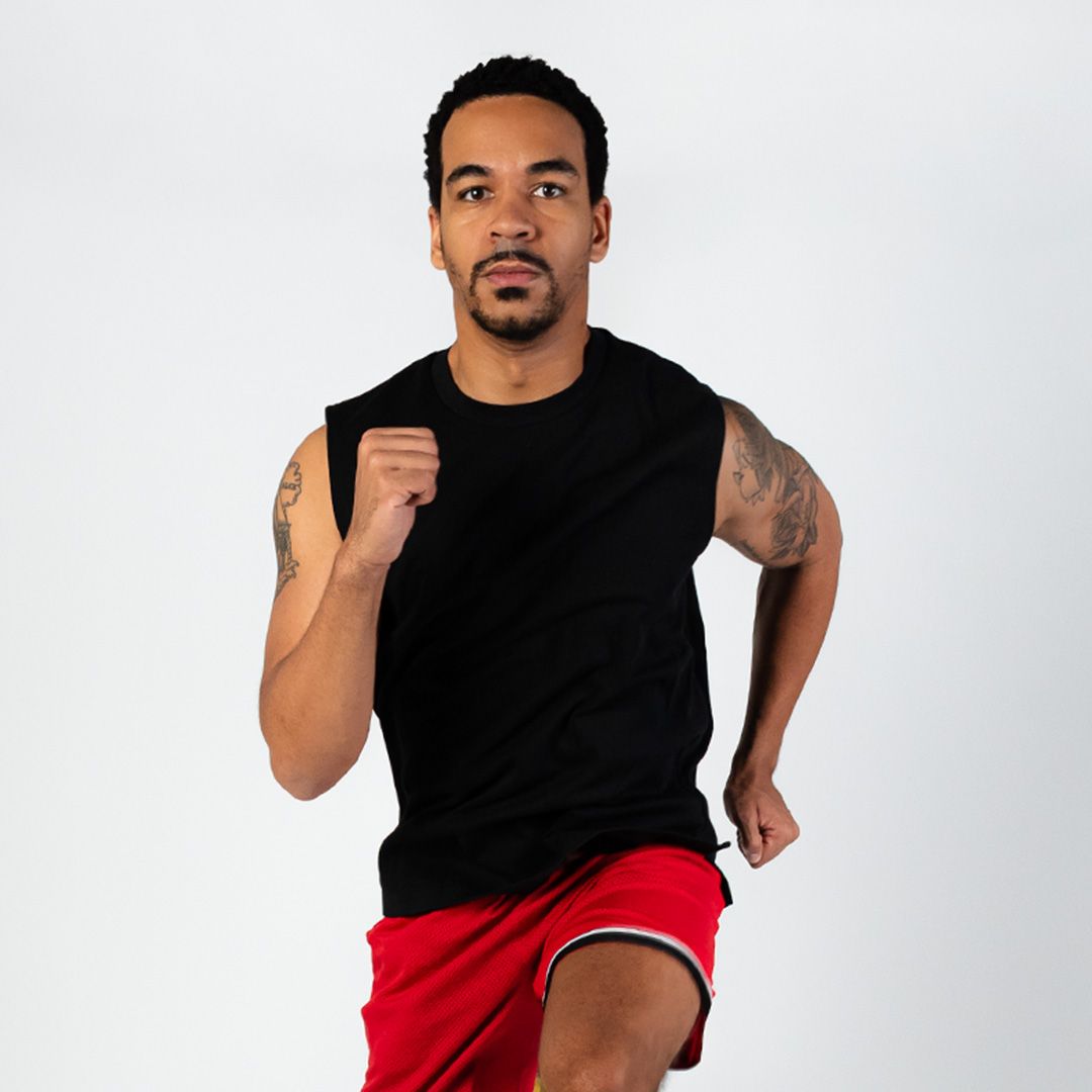 A man in a black tank top and red shorts is running
