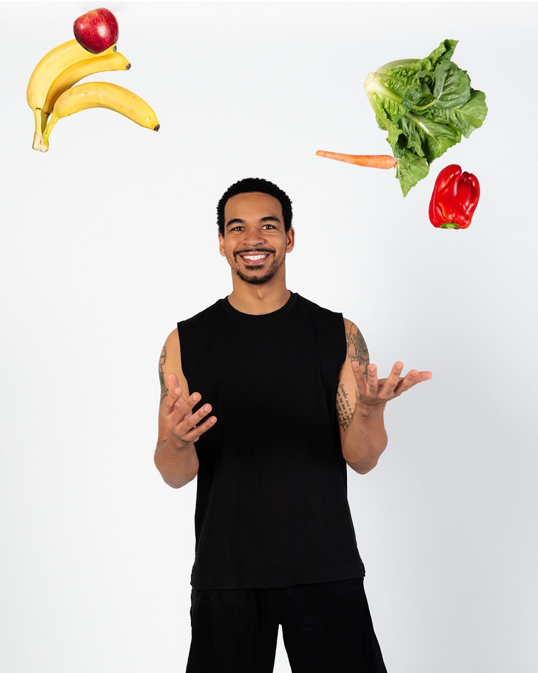 A man is juggling fruits and vegetables in the air.