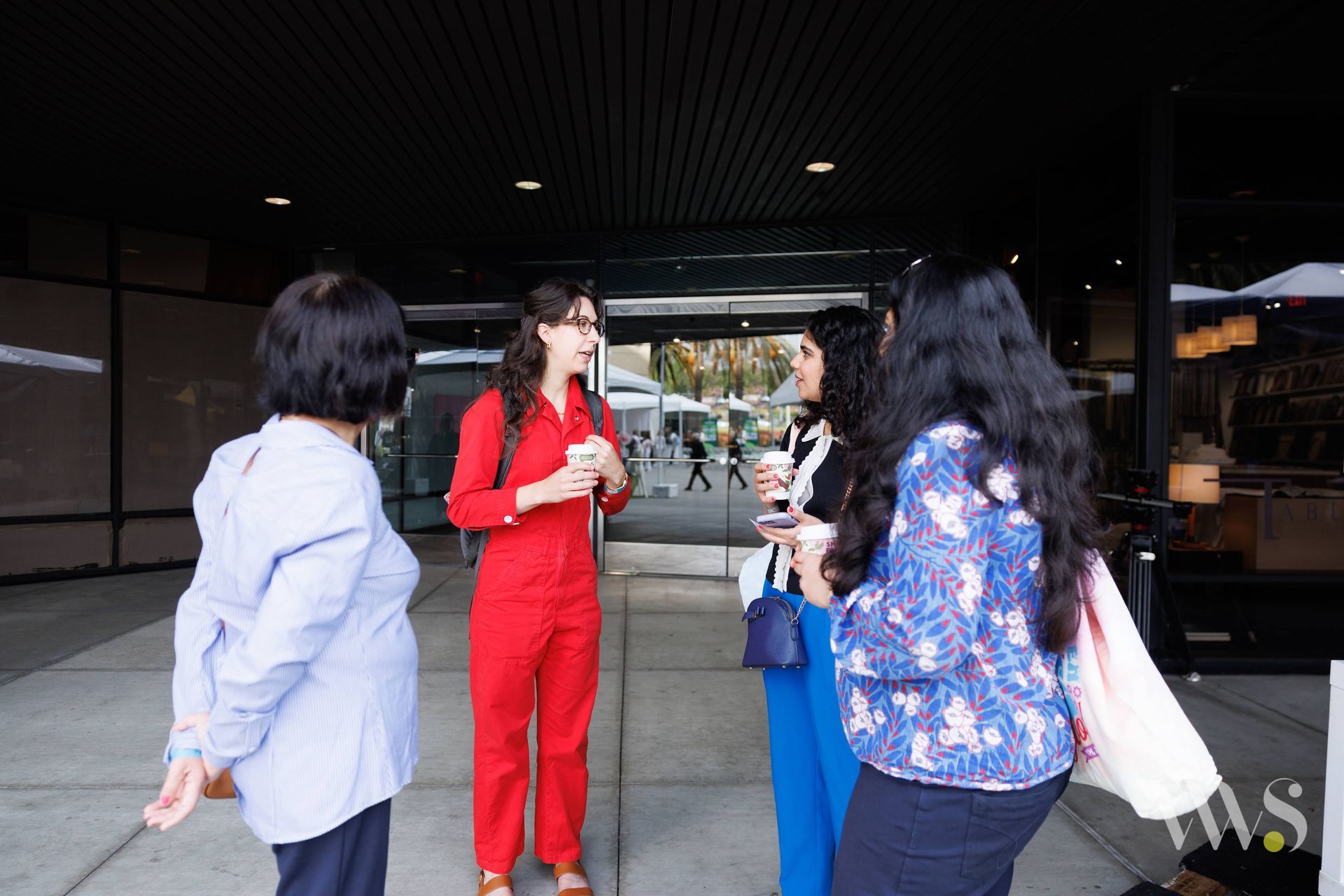 A group of women are standing outside of a building talking to each other.