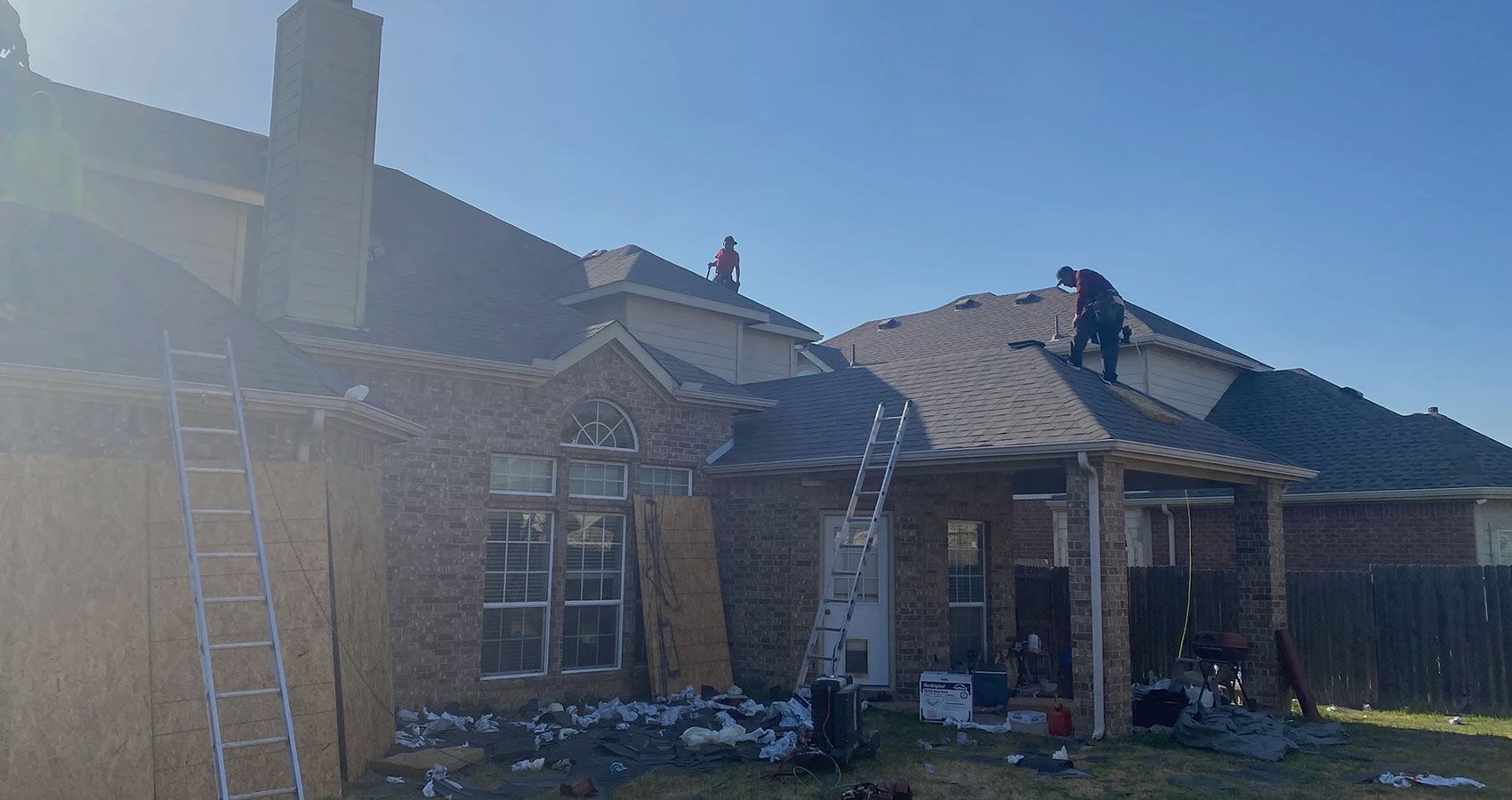 A couple of men are working on the roof of a house.