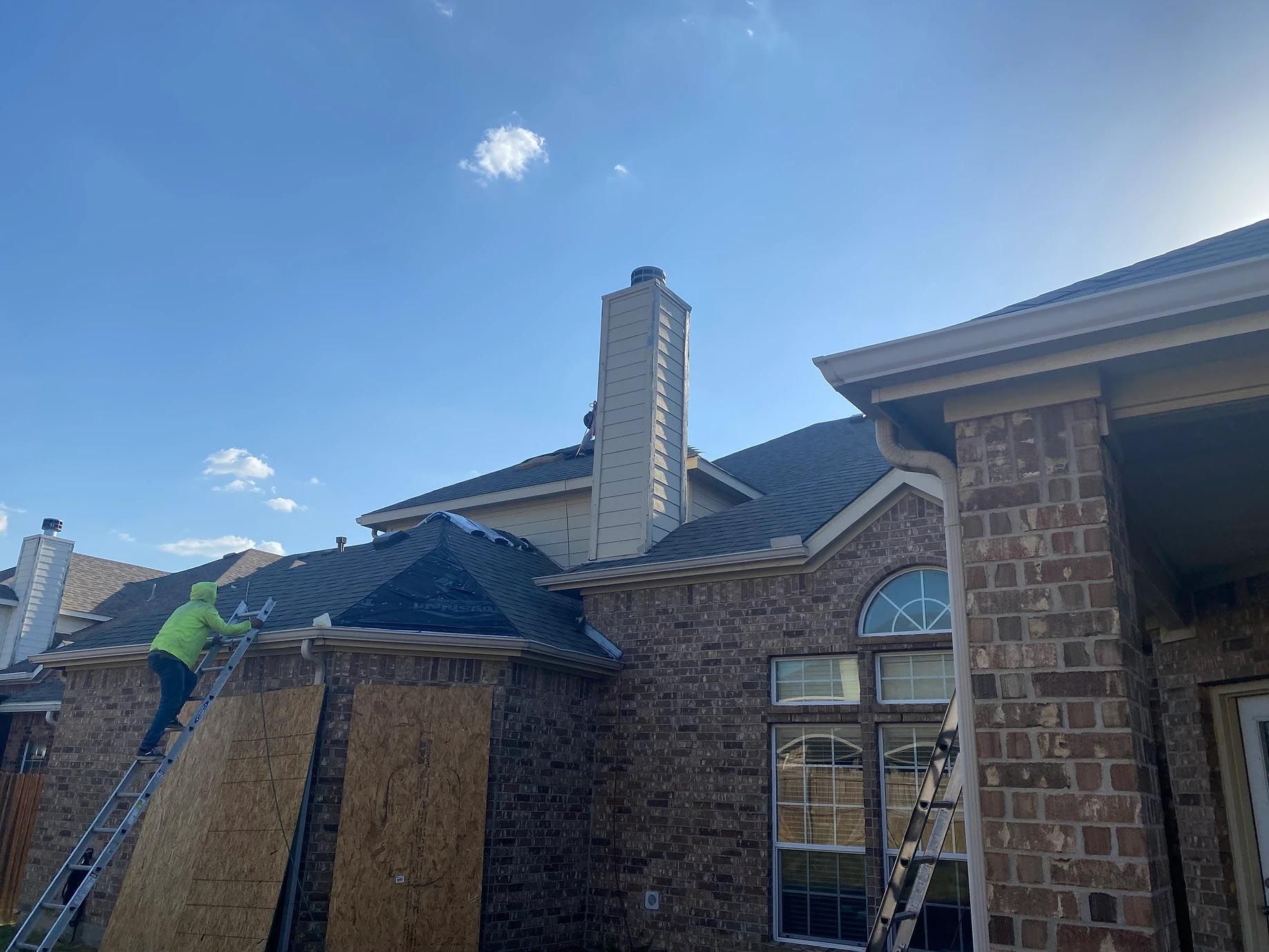 A man is working on the roof of a brick house.