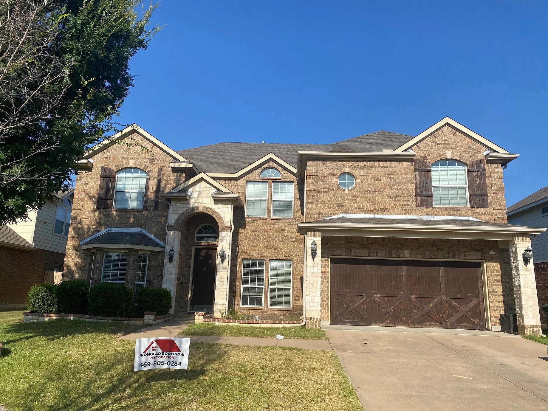 A large brick house with a sign in front of it.