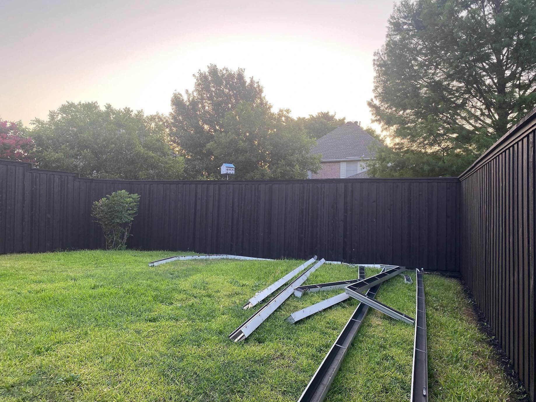 A black fence surrounds a lush green yard.