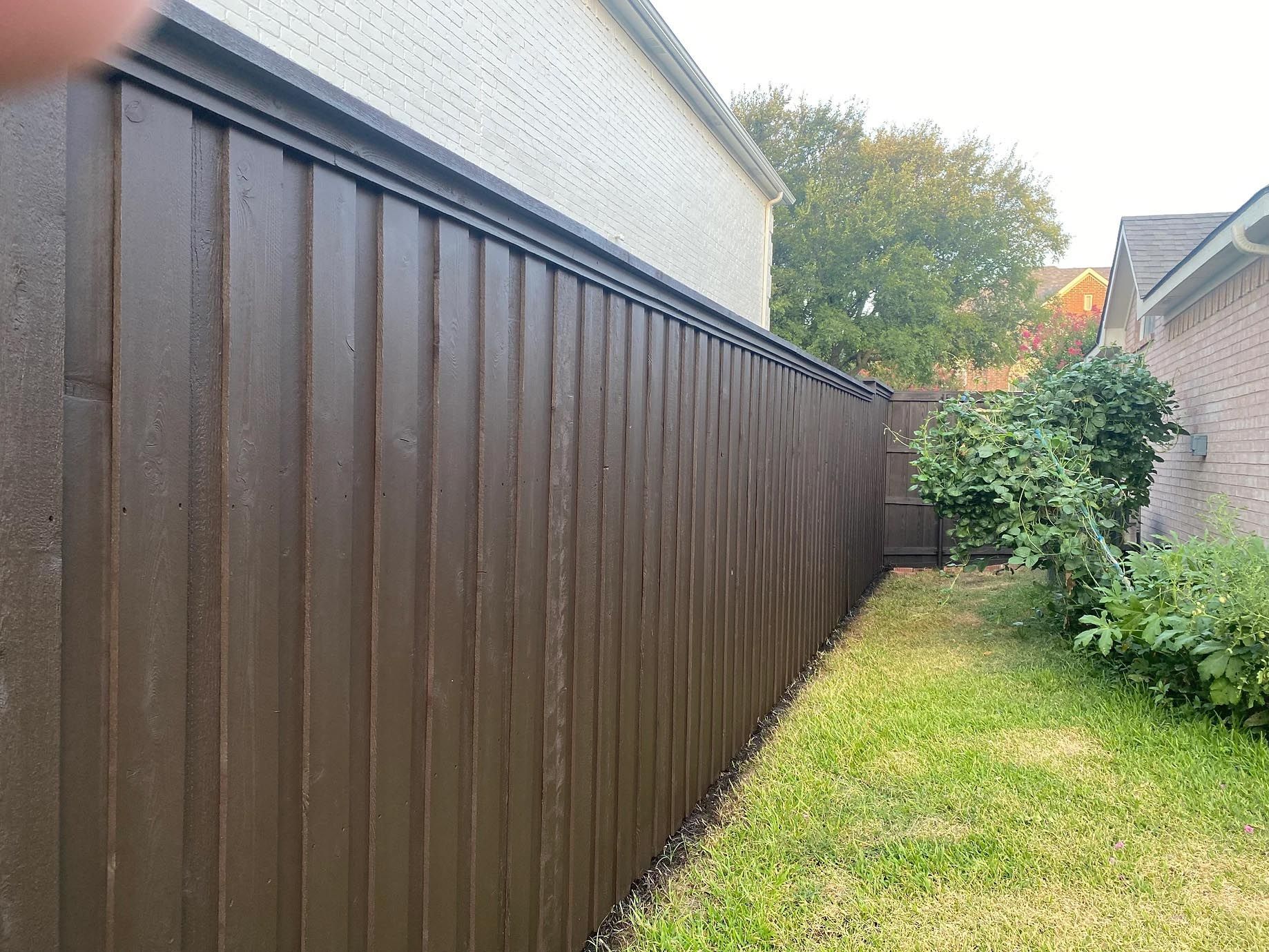 A brown wooden fence is in the backyard of a house.