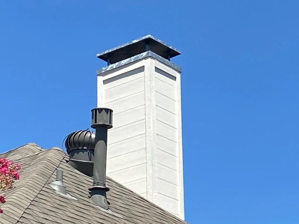 A chimney on the roof of a house with a blue sky in the background.